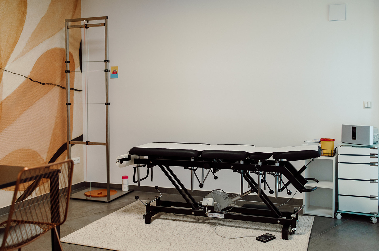 Behandlungsliege und Equipment vor pfirsichfarbener Wand